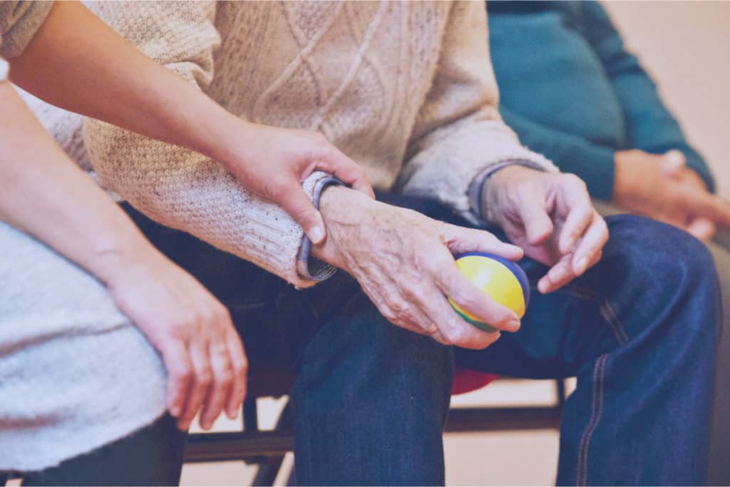 Woman grabbing sick old man's hand with a sleeping disorder